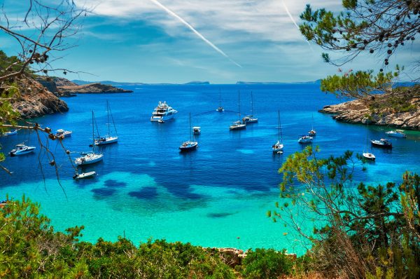 Sailboat and a yacht at Cala Salada turquoise lagoon cove